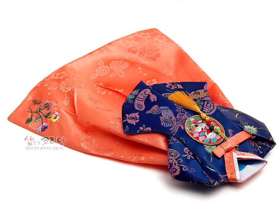 [텍스트: 샵오브코리아 / 대한민국의 품격까지 전합니다.] 주홍색 비단 치마와 국화·모란 문양, 남색 비단 당의에 오방색 수실로 놓은 학·꽃 자수와 노란 술 노리개 장식의 한복형 와인 커버 이미지 설명