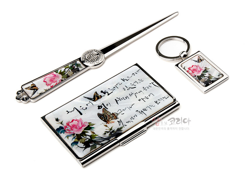 [텍스트: 미묘하게 물들어있는 / 홍색의 모란이 피어 / 향기를 내뿜어 나비의 시선이 멎은 곳에는 / 행복과 기쁨이 가득하리라] 금속 테두리에 자개 느낌 광택을 더하고 담채 풍의 분홍 모란과 나비, 한글 서예가 조화를 이룬 명함집·편지칼·열쇠고리 세트 이미지 설명