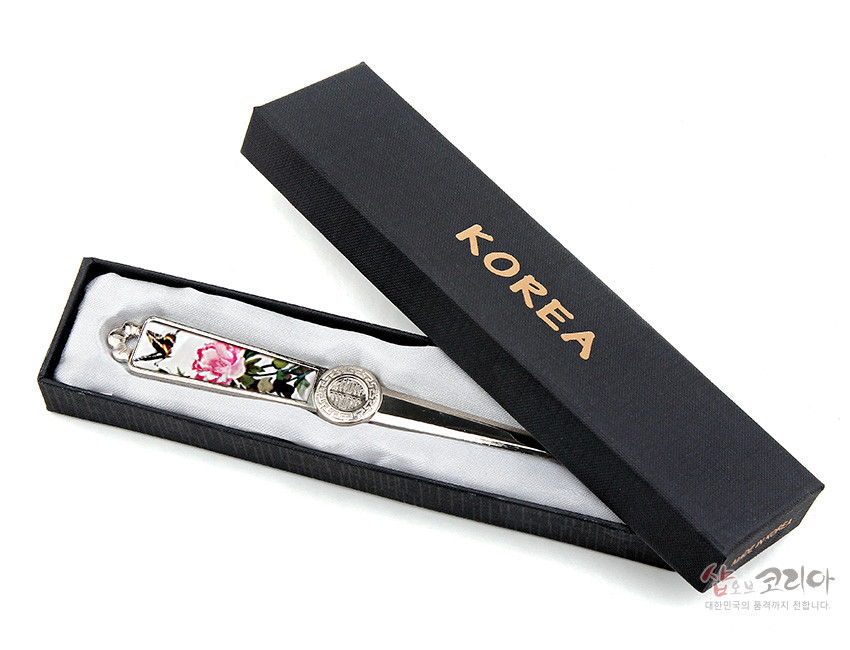 [텍스트: KOREA] 금속 재질 손잡이에 자개 상감으로 표현된 분홍 꽃과 나비 문양, 중앙 원형 전통 건축물 부조 장식이 돋보이는 편지칼 이미지 설명