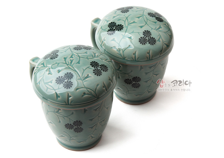 [텍스트: 샵오브코리아 대한민국의 품격까지 전합니다.] 청자 재질에 흑색 국화와 담녹색 덩굴무늬를 상감 기법으로 장식한 뚜껑 머그다기잔 세트 이미지 설명