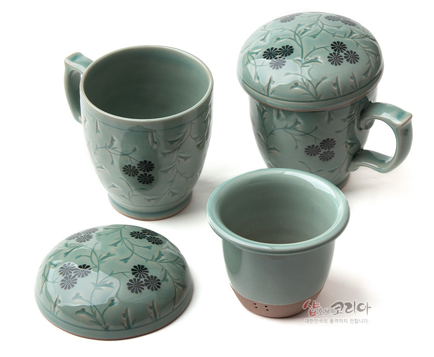 [텍스트: 샵오브코리아 대한민국의 혼과 정까지 전합니다.] 옅은 청녹색 청자 재질에 흑색 국화와 덩굴무늬를 상감 기법으로 새긴 머그다기잔과 거름망, 뚜껑 세트 모습