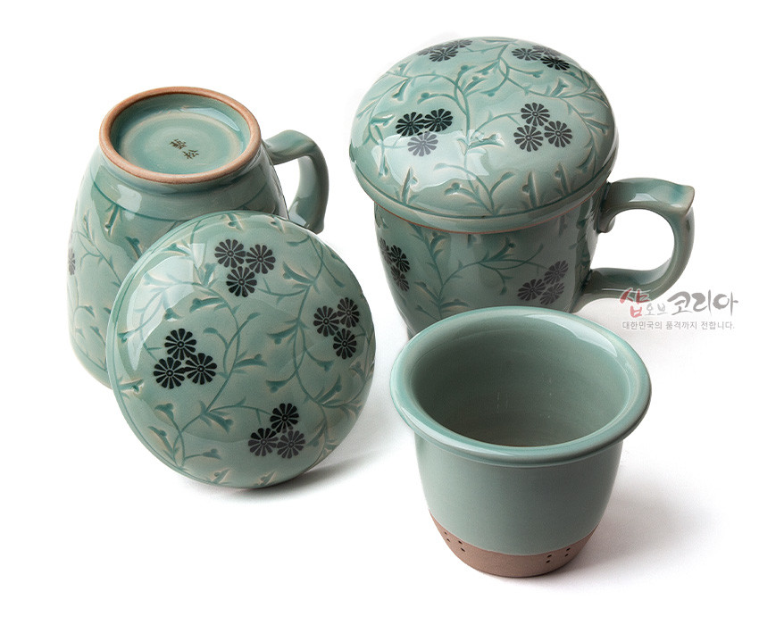 [텍스트: 샵오브코리아 대한민국의 혼 깃까지 전합니다.] 담녹색 청자 재질에 흑색 국화와 줄기 문양을 상감기법으로 넣은 뚜껑 머그다기잔 세트 구성 이미지 설명