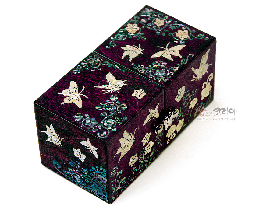 [텍스트: 샵오브코리아 대한민국의 품격까지 전합니다.] 보라색 한지 바탕 위 자개 상감 기법으로 나비와 당초·화문을 정교하게 장식한 쌍합 형태 전통 보석함 이미지 설명
