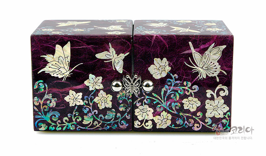 [텍스트: 샵오브코리아 대한민국의 품격까지 전합니다.] 보라색 한지 바탕 위 자개 상감으로 표현된 당초와 나비·꽃 문양이 돋보이는 쌍합 형태 보석함 디자인