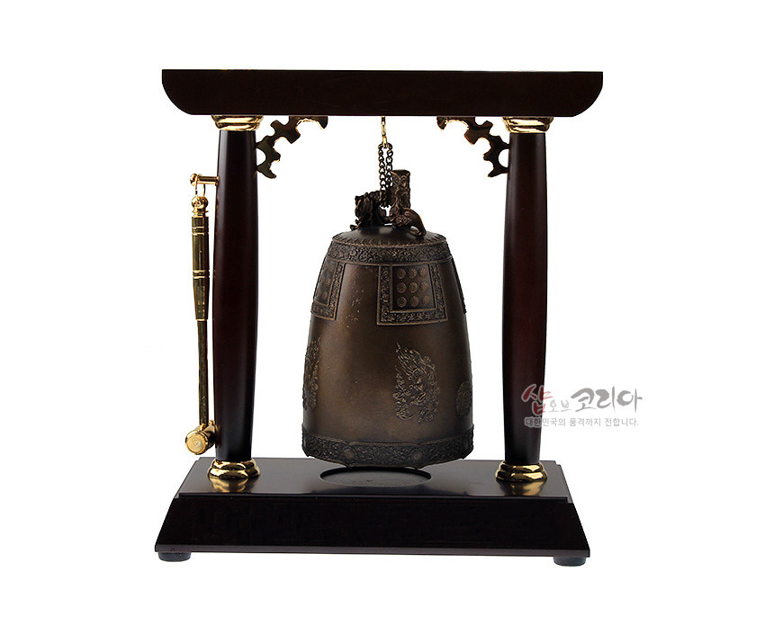 [텍스트: 샵오브코리아 대한민국의품격까지전합니다.] 청동 소재 미니 에밀레종과 목재 거치대, 금속 장식 및 용무늬·보상화문 양각 장식된 전통 종 인테리어 소품 모습