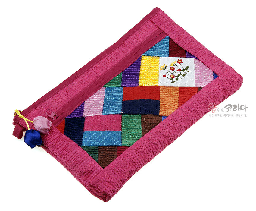 [텍스트: 샵오브코리아 대한민국의 품격까지 전합니다.] 진분홍 누비 원단 위 다채로운 색상의 조각보 패치워크와 국화 문양 자수, 실크 매듭 장식 지퍼가 조화를 이룬 패브릭 파우치 이미지 설명