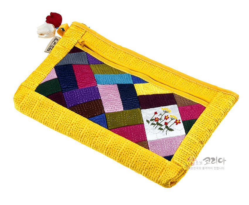 [텍스트: 샵오브코리아] 노란색 누비 바탕 위에 다채로운 색상의 조각보 패턴을 더하고, 흰색 칸에 꽃 자수 문양을 수놓은 패브릭 파우치 디자인