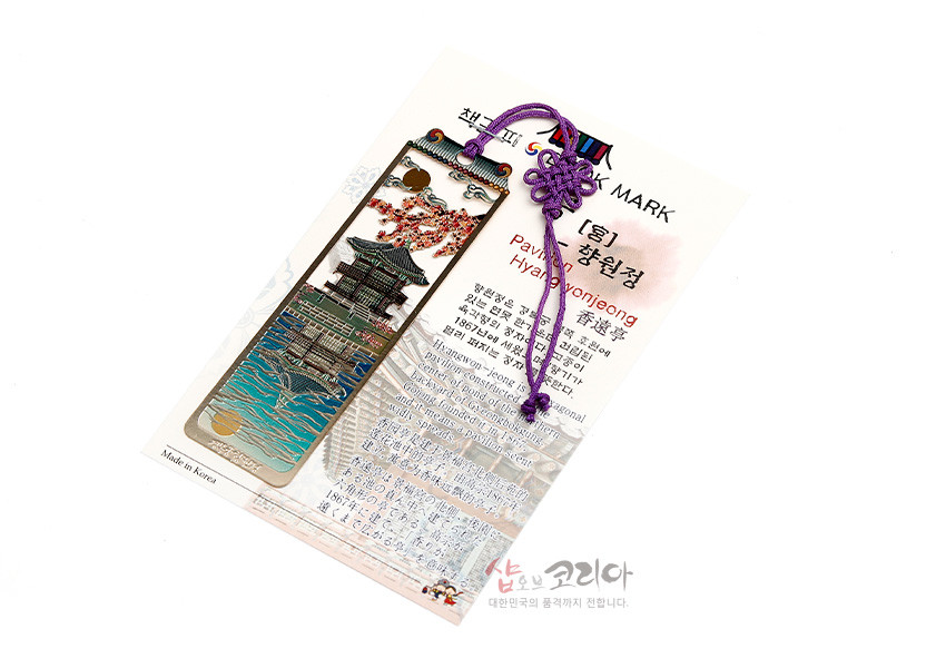 [텍스트: BOOK MARK, Pavilion Hyangwonjeong, Made in Korea] 금속 재질 위 채색 기법으로 궁과 향원정, 호수와 노을, 벚꽃 문양을 표현하고 보라색 전통 매듭끈을 장식한 직사각형 책갈피 이미지 설명