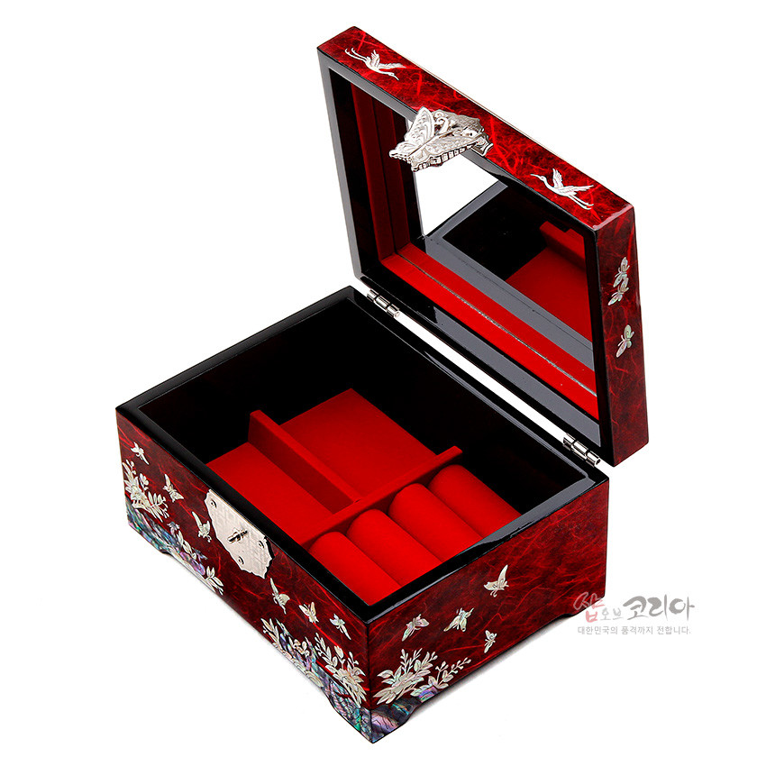 [텍스트: 샵오브코리아 대한민국의 품격까지 전합니다.] 적색 한지와 옻칠 바탕 위 자개 상감으로 송학과 나비, 매화 문양을 장식하고 내부는 붉은 벨벳 칸막이와 거울을 더한 직사각 보석함 이미지 설명