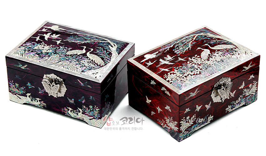 [텍스트: 샵오브코리아 대한민국의 품격까지 전합니다.] 적색 옻칠 바탕 위 자개 상감 기법으로 송학·나비·산수 문양을 정교하게 표현한 직사각 보석함 연출 이미지