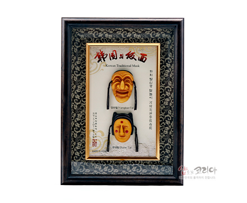 [텍스트: Korean Traditional Mask / 양반탈 Yangban Tal / 부네탈 Bune Tal / MADE IN KOREA] 짙은 목재 액자와 금색 테두리, 당초무늬 배경 위에 노란빛 하회탈 두 점을 입체 부조로 배치한 세로형 장식 액자형 공예품