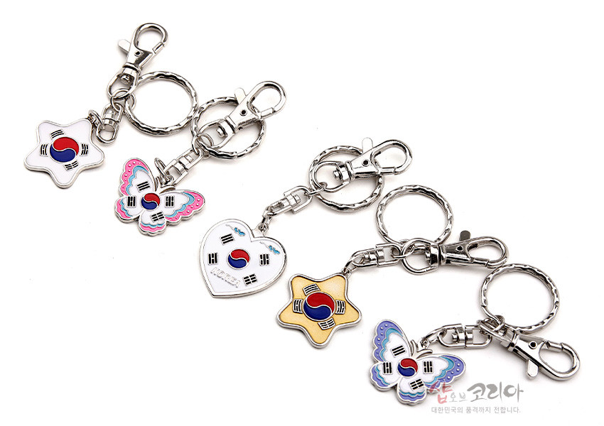 [텍스트: 샵오브코리아, 대한민국의 품격까지 전합니다.] 금속 재질의 열쇠고리에 별, 하트, 나비 모양 태극기 문양 에나멜 장식이 달린 5종 세트 구성 이미지 설명