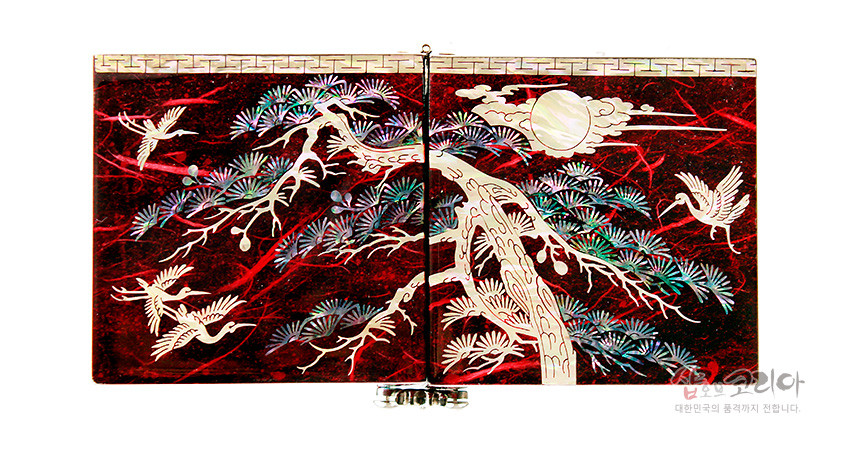 [텍스트: 샵오브코리아 대한민국의 품격까지 전합니다] 붉은 옻칠 바탕 위 자개 상감 기법으로 소나무와 학, 해와 구름 문양을 섬세하게 표현한 한지 쌍합 정면 이미지