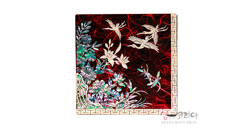 [텍스트: 샵오브코리아 대한민국의 품격까지 전합니다] 붉은 옻칠 바탕 위 자개 상감으로 학과 소나무, 꽃문양을 섬세하게 표현한 전통 한지 쌍합 상단 장식 이미지