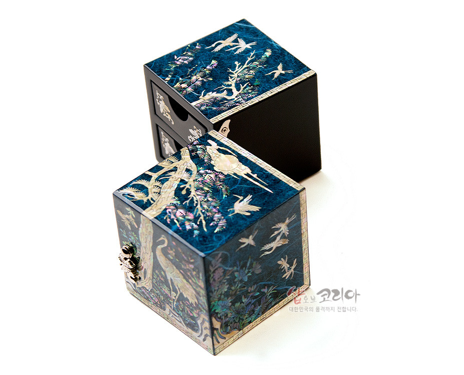 [텍스트: 샵오브코리아 대한민국의 품격까지 전합니다.] 청색 한지 위에 자개 상감으로 소나무와 학, 구름을 섬세히 표현한 직육면체 쌍합 보석함 디자인