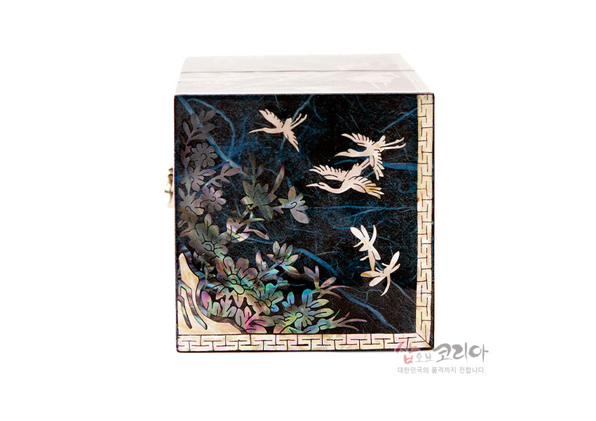 [텍스트: 샵오브코리아 대한민국의 품격까지 전합니다.] 청색 옻칠 한지 바탕 위 자개 상감으로 송학과 소나무, 구름을 섬세하게 표현하고 가장자리에 전통 기하학 문양을 둘러 장식한 사각 쌍합 정면 모습