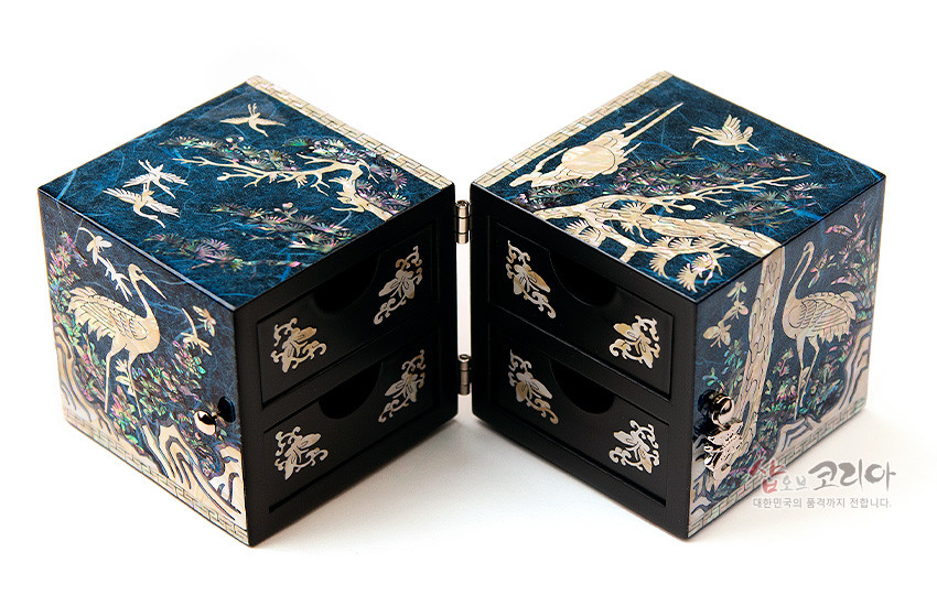 [텍스트: 숍오브코리아 대한민국의 품격까지 전합니다.] 청색 한지 배경 위 자개 상감으로 소나무와 학, 구름과 꽃을 섬세하게 표현한 직사각형 쌍합 보석함, 나전 문양 손잡이와 금속 경첩 장식 구성