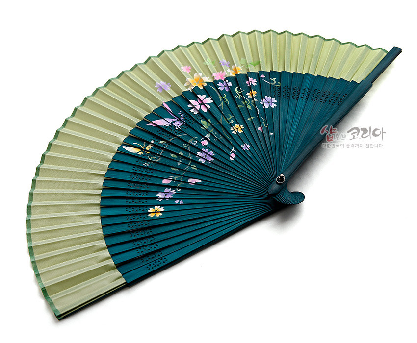 [텍스트: 샵오브코리아 대한민국의 품격까지 전합니다.] 녹색과 청록색 실크 주름 위에 수공 나비와 꽃무늬가 섬세하게 그려진 합죽선 형태 접이식 부채 이미지 설명