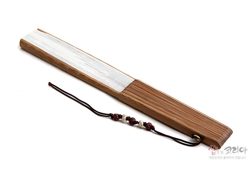 [텍스트: 샵오브코리아 대한민국의 품격까지 전합니다.] 대나무살 구조와 흰색 종이 마감이 어우러진 접선, 끝부분 매듭 끈과 구슬 장식이 더해진 전통 부채 디자인