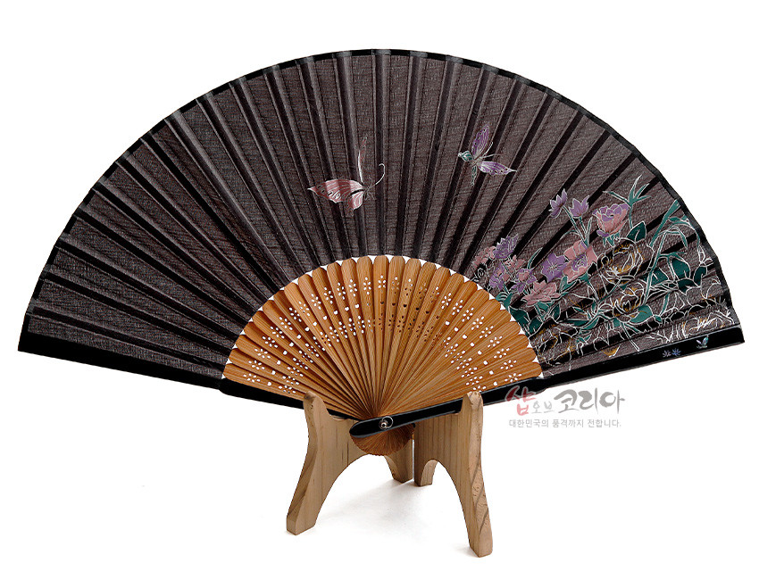 [텍스트: 샵오브코리아 대한민국의 품격까지 전합니다.] 검은 비단 선면 위에 자개 느낌의 핑크·보라 나비와 모란 꽃 문양을 섬세한 채색으로 표현하고, 대나무 살대에 정교한 타공 장식을 더한 전통 합죽선 디자인