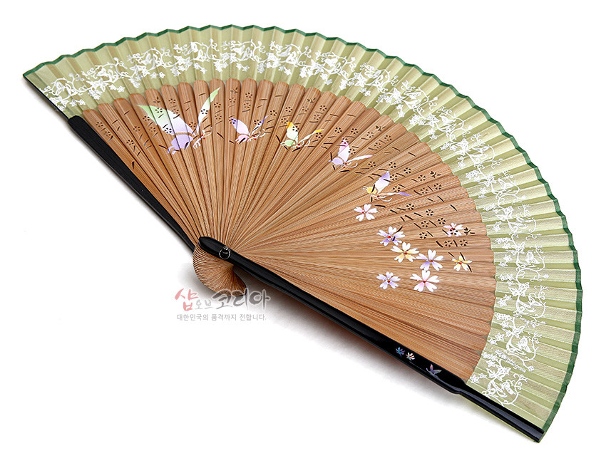 [텍스트: 샵오브코리아 대한민국의 품격까지 전합니다.] 연녹색 실크에 흰색 식물 문양 인쇄, 황색 대나무살에 나비·꽃 자개 상감과 천공 장식이 더해진 전통 수공 부채 디자인