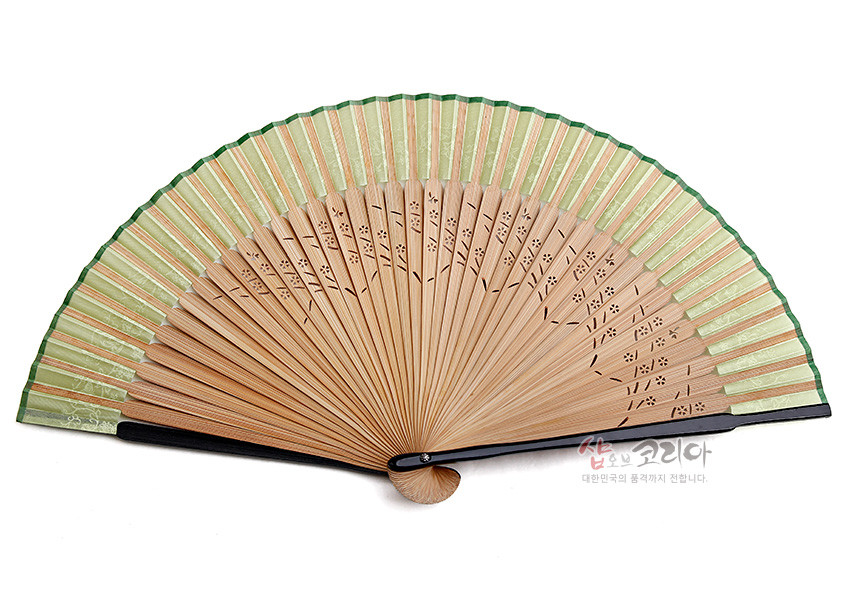 [텍스트: 샵오브코리아 대한민국의 품격까지 전합니다.] 연녹색 실크 부채살과 황색 대나무 살의 천공 기법 문양, 검정 손잡이와 자개 장식이 조화를 이룬 전통 수공 부채 이미지 설명