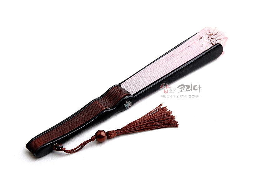 [텍스트: 샵오브코리아 대한민국의 품격까지 전합니다.] 나뭇결 살대와 흑색 손잡이, 분홍 비단 접힘 살, 자개 꽃문양 장식과 갈색 술 매듭이 조화를 이룬 접이식 부채 모습