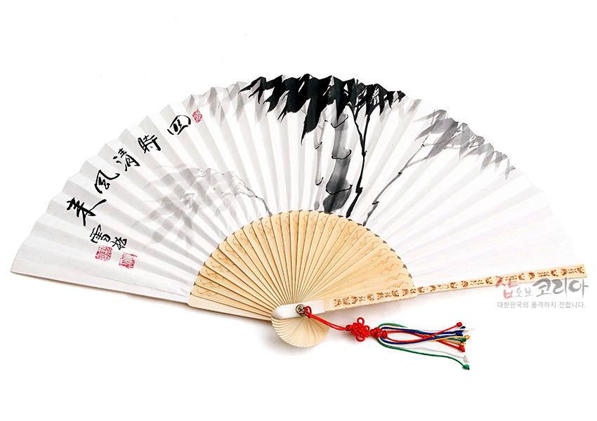 [텍스트: 샵오브코리아 대한민국의 품격까지 전합니다.] 대나무 살과 흰 한지 위 수묵 산수화와 한문 서예, 붉은 도장 인장, 손잡이 부분 정교한 조각무늬와 오방색 술 매듭 장식 부채 이미지 설명