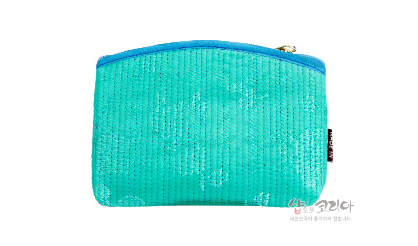 [텍스트: 샵오브코리아 대한민국의 품격까지 전합니다.] 청록색 누비 천에 세로 누빔선과 은은한 전통 문양이 들어간 직사각형 동전지갑, 하늘색 파이핑과 금속 지퍼 장식 디자인