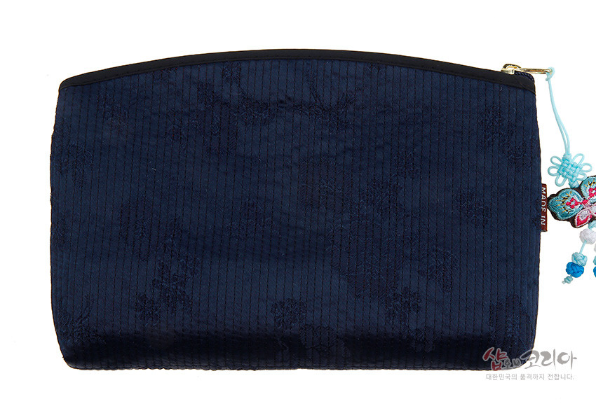 [텍스트: MADE IN, 샵오브코리아 대한민국의 품격까지 전합니다] 감색 누비 원단 위 세로 누빔선과 은은한 꽃문양, 금속 지퍼와 청색 나비 매듭 장식이 있는 티슈 지갑 모습