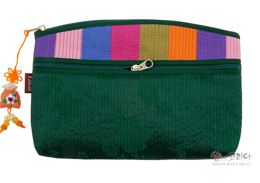 [텍스트: KOREA, 샵오브코리아 대한민국의 품격까지 전합니다.] 짙은 녹색 누비 원단 위 색동 누비 패턴과 금속 지퍼, 노리개 장식이 조화된 전통 티슈 지갑 이미지 설명