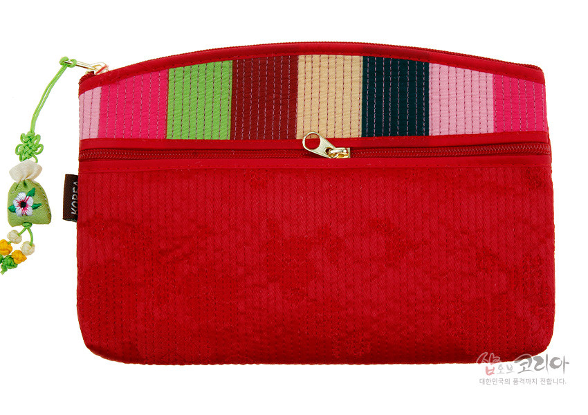 [텍스트: 샵오브코리아 대한민국의 품격까지 전합니다.] 붉은색 누비 원단에 분홍·초록·밤색·베이지·남색 색동 배색과 금속 지퍼, 자수 매듭 장식이 조화된 직사각형 티슈 지갑 이미지 설명