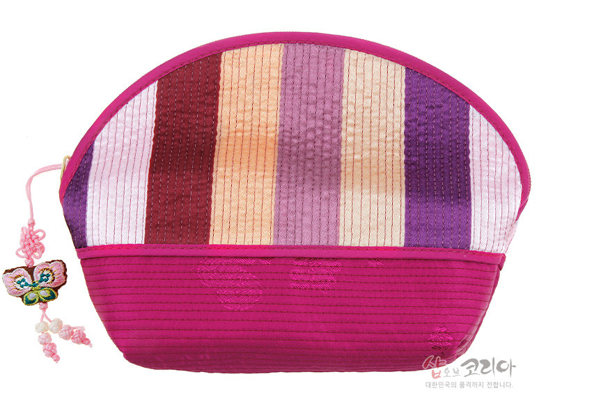 [텍스트: 샵오브코리아 대한민국의 품격까지 전합니다.] 색동 누비 비단으로 구성된 반원형 파우치, 아래쪽 가로 누비와 동그라미 자수, 지퍼에 나비 전통 매듭 장식 달린 디자인