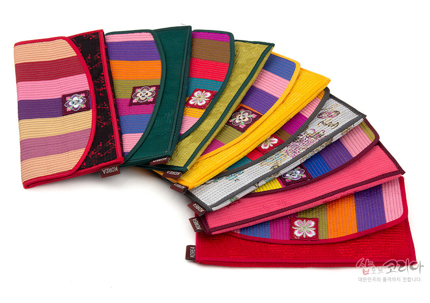 [텍스트: KOREA] 색동 비단 누비 기법으로 제작된 다양한 색상의 장지갑, 중앙 꽃 자수 장식과 대비색 배색 테두리가 돋보이는 디자인