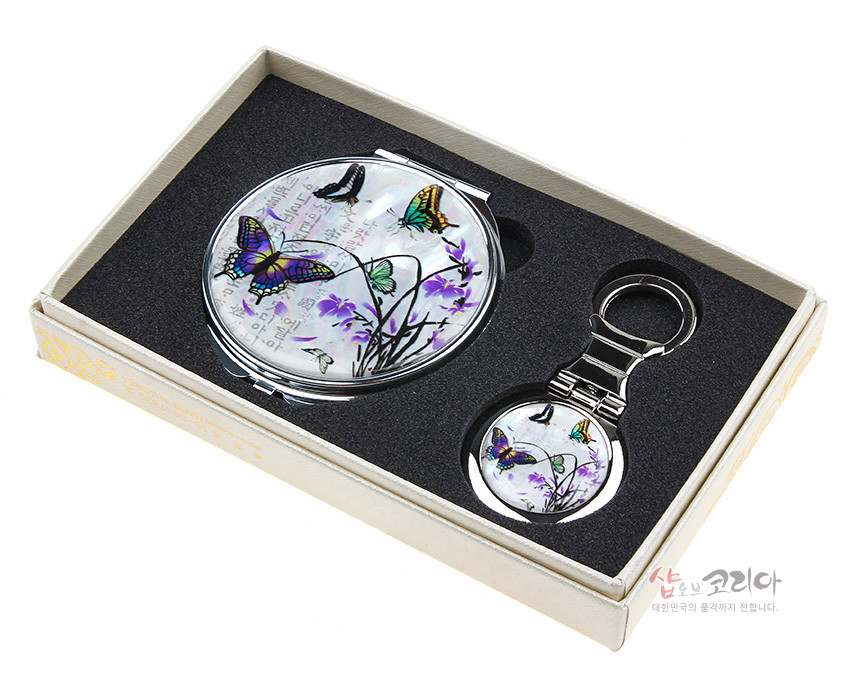 [텍스트: 샵오브코리아 대한민국의 품격까지 전합니다.] 자개와 옻칠로 표현한 난초와 나비 문양, 오팔빛 자개 배경과 은색 금속 테두리가 조화로운 원형 손거울 2종 세트 이미지 설명