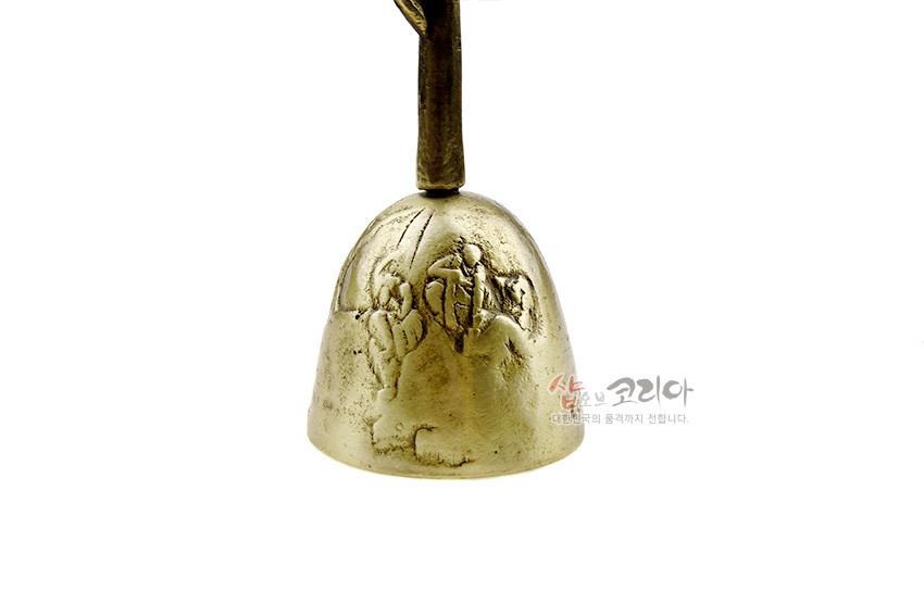 [텍스트: 샵오브코리아 대한민국의 품격까지 전합니다.] 황동 재질 종 몸체에 인물 부조와 전통 문양을 섬세하게 양각한 솟대 형상 금속 공예 장식종 모습