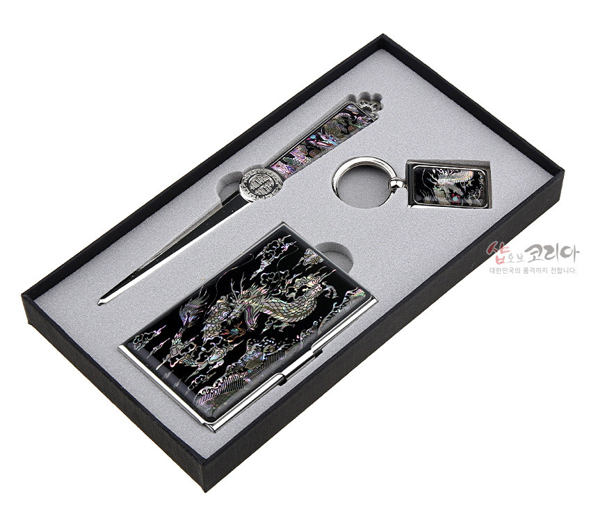 [텍스트: 샵코리아 대한민국의 품격까지 전합니다] 검은 바탕 금속 위에 자개 상감 기법으로 오색 용과 구름 문양을 넣은 명함집·책갈피·열쇠고리 3종 세트 모습