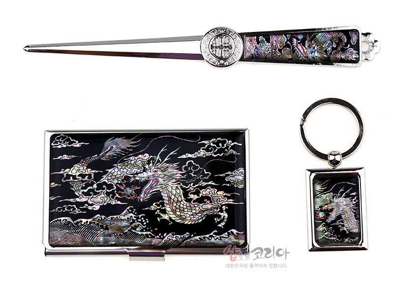 [텍스트: 샵오브코리아 대한민국의 품격까지 전합니다.] 검은 바탕 위 금속 테두리에 자개 상감 기법으로 오색 용과 구름, 파도 문양을 넣은 명함집·지칼·열쇠고리 3종 세트 구성