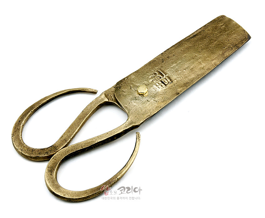 [텍스트: 복] 황동빛 금속 재질의 전통 엿가위, 두 개의 곡선형 손잡이와 넓은 날, 거친 망치질 질감과 상단 한글 음각 장식이 돋보이는 공예품형 디자인