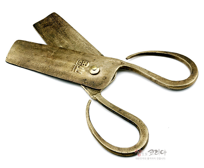 [텍스트: 福] 황동빛 금속 재질의 전통 엿가위, 투박한 표면 질감과 곡선형 손잡이, 몸체에 한자 복(福) 양각 문양이 더해진 공예품 묘사