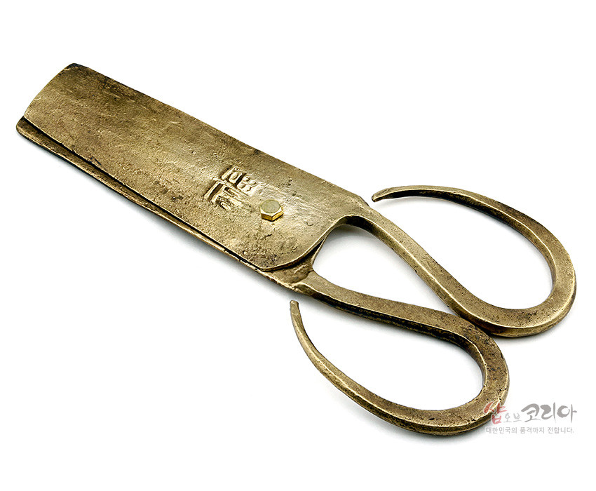 [텍스트: 福] 황동빛 금속 재질의 전통 엿가위, 투박한 망치질 질감과 유려한 곡선 손잡이, 몸체에 새겨진 한자 음각 문양이 돋보이는 공예품