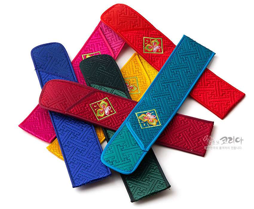 [텍스트: 샵오브코리아 대한민국의 품격까지 전달합니다] 비단 누비 기법으로 짠 기하학 문양의 다채로운 색상 부채 주머니와 중앙 꽃·나비 자수 장식 모습