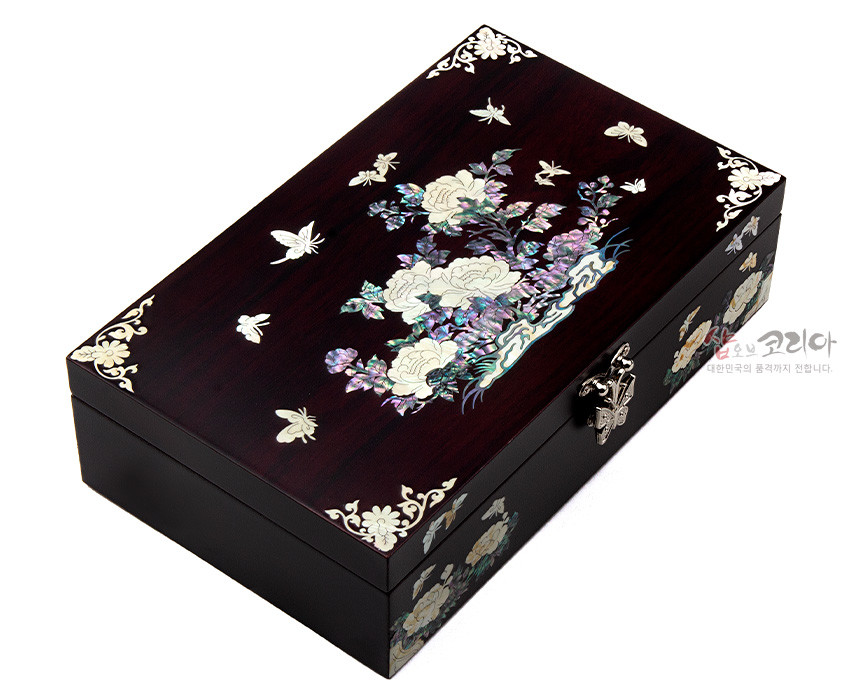 [텍스트: 샵오브코리아 대한민국의 품격까지 전합니다.] 짙은 와인색 옻칠 목재 위 자개 상감 기법으로 목단과 나비 문양을 섬세하게 표현한 직사각형 무광 보석함