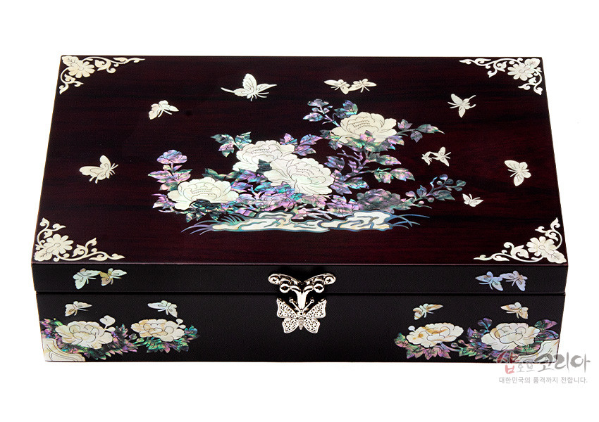 [텍스트: 샵오브코리아 대한민국의 혼까지 전하다.] 짙은 와인색 옻칠 나무 위 자개 상감 기법으로 목단과 나비, 구름형 꽃문양을 섬세하게 배치한 직사각형 다용도함 디자인
