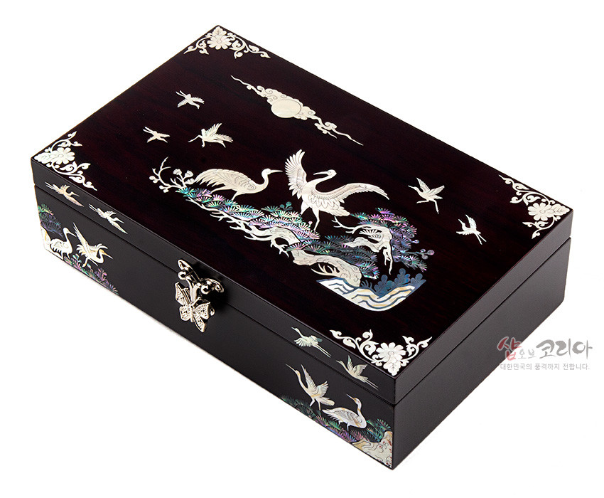 [텍스트: 샵오브코리아 대한민국의 품격까지 전합니다.] 짙은 옻칠 바탕 위 자개 상감으로 소나무와 학, 구름과 달 문양을 표현한 직사각형 나전칠기 보석함 디자인