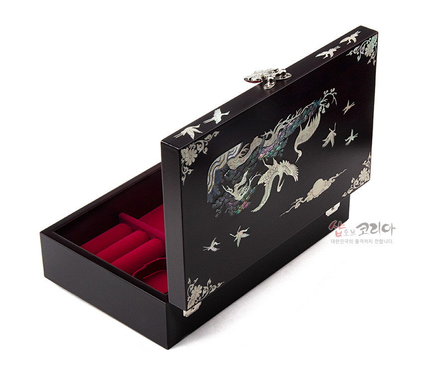 [텍스트: 샵오브코리아 대한민국의 품격까지 전달합니다.] 짙은 옻칠 바탕 위 자개 상감으로 소나무와 학, 구름 문양을 섬세하게 표현한 직사각형 나전칠기 보석함 내부 붉은 칸막이 구성