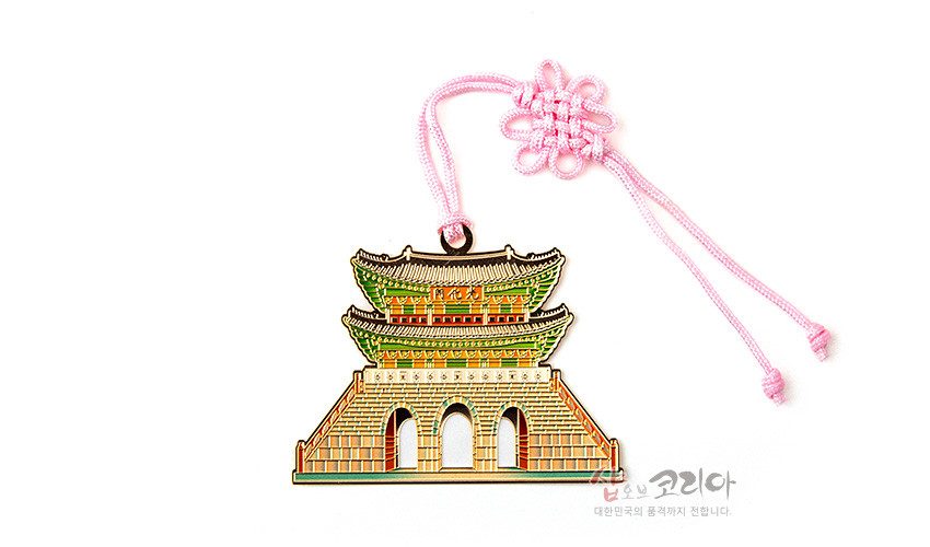[텍스트: 샵오브코리아 대한민국의 품격까지 전달합니다.] 금속 재질로 구현한 전통 성문 문양 장식에 분홍색 전통 매듭 끈을 더한 다채로운 채색의 책갈피 형태 이미지