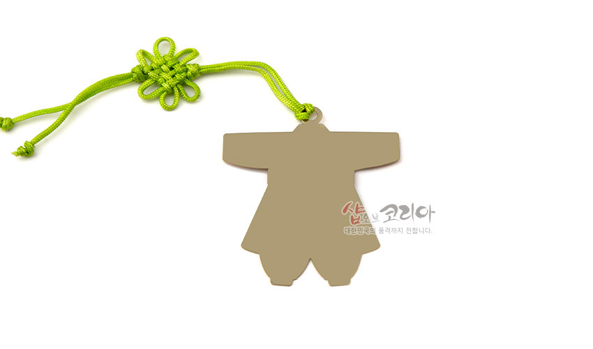[텍스트: 샵오브코리아 대한민국의 품격까지 전합니다.] 금속 재질 아동 한복 실루엣 책갈피와 연두색 전통 매듭 장식, 심플한 무광 표면 디자인