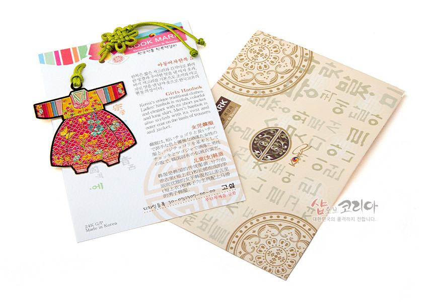 [텍스트: BOOK MARK, Girls Hanbok, 24K GP, Made in Korea] 금속 재질 아동 색동한복 모양 책갈피와 연두색 전통 매듭, 한글과 전통 문양 인쇄 종이 패키지 구성 이미지 설명