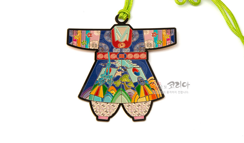 [텍스트: 샵오브코리아] 금속 재질 위 채색 기법으로 표현된 아동 색동한복 모양 책갈피, 구름·산수·꽃 전통 문양과 분홍색 비즈 장식, 연두색 매듭 끈 포인트 구성